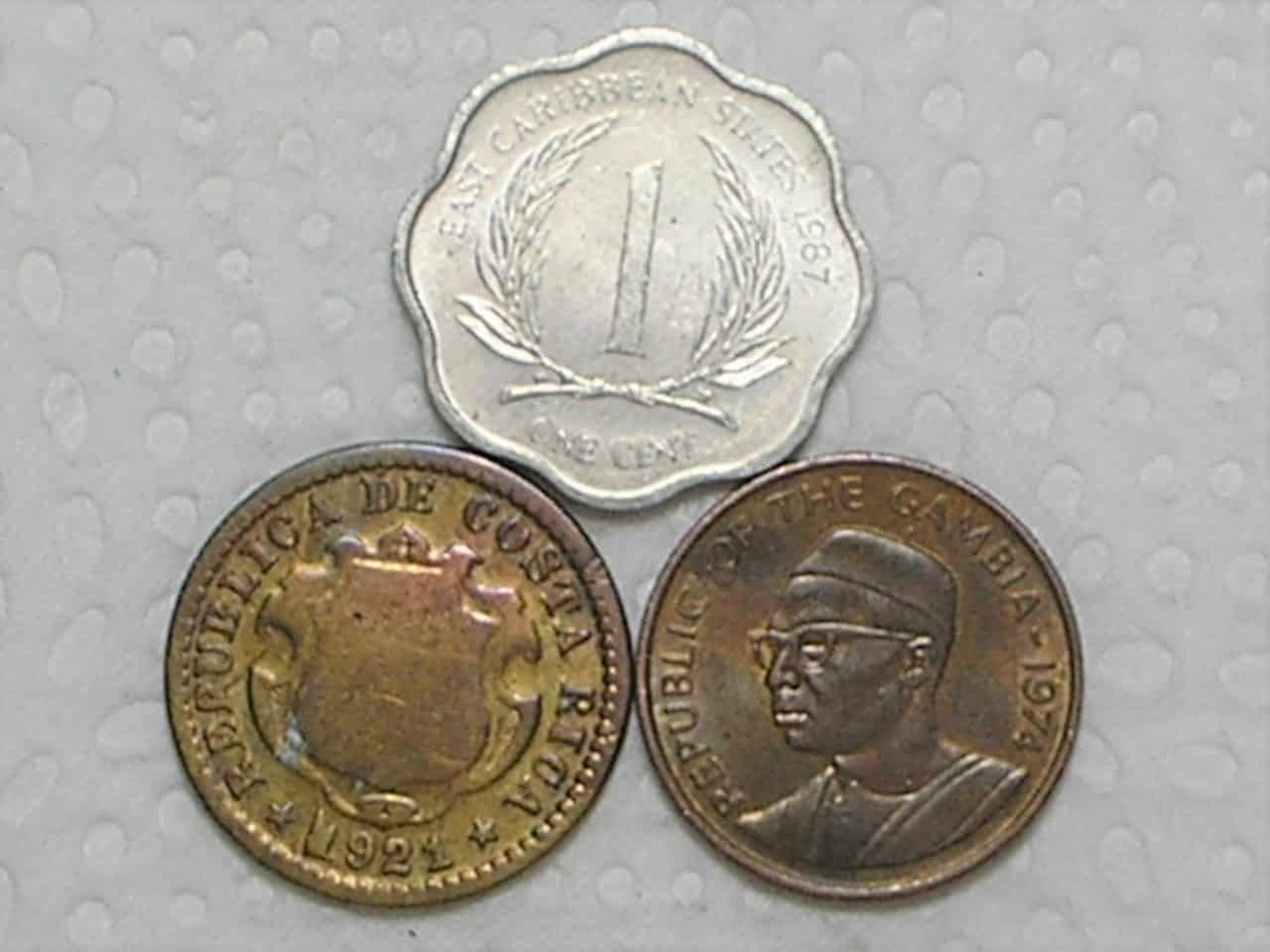 3 Moedas) East Caribean States 1 Cent - 1978 + Gambia 1 Butut - 1974 + Costa Rica 10 Centimos - 1921 / box25